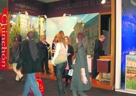 Varias personas pasan junto al ‘stand’ de San Lorenzo de El Escorial en FITUR / AYTO. SAN LORENZO